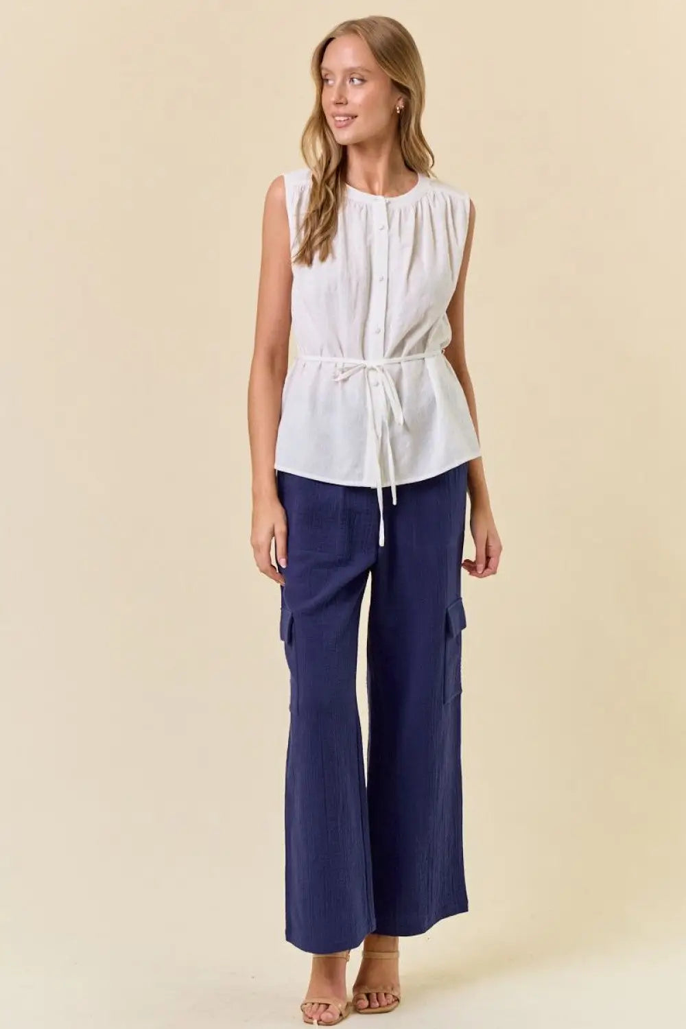 Woman wearing white sleeveless top and blue cargo pants in women’s boho chic clothing style