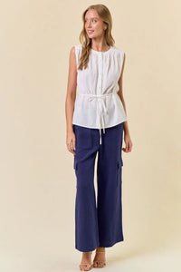 Woman wearing white sleeveless top and blue cargo pants in women’s boho chic clothing style