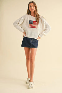 Woman wearing a white flag knitted sweater top with denim skirt, perfect for women’s boho chic clothing from Shop Daisy