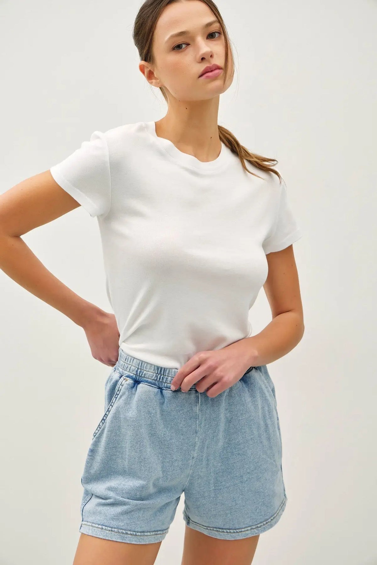 Woman wearing white t-shirt and light blue shorts showcasing Daisy Lane’s garment dye cotton shorts