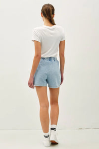Woman wearing white t-shirt and light blue denim shorts from Daisy Lane’s garment dye cotton collection