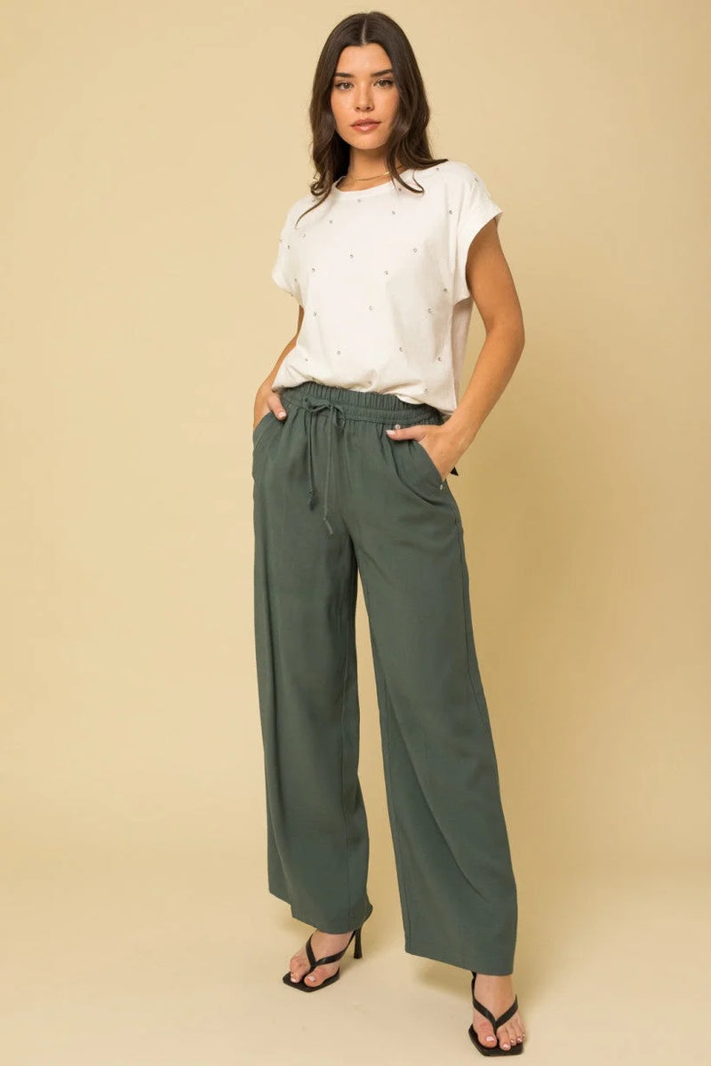 Woman in white t-shirt and green wide leg track pants with pockets detail