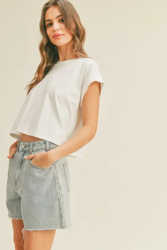 Woman in a white round neck cuffed sleeve top and light blue denim shorts