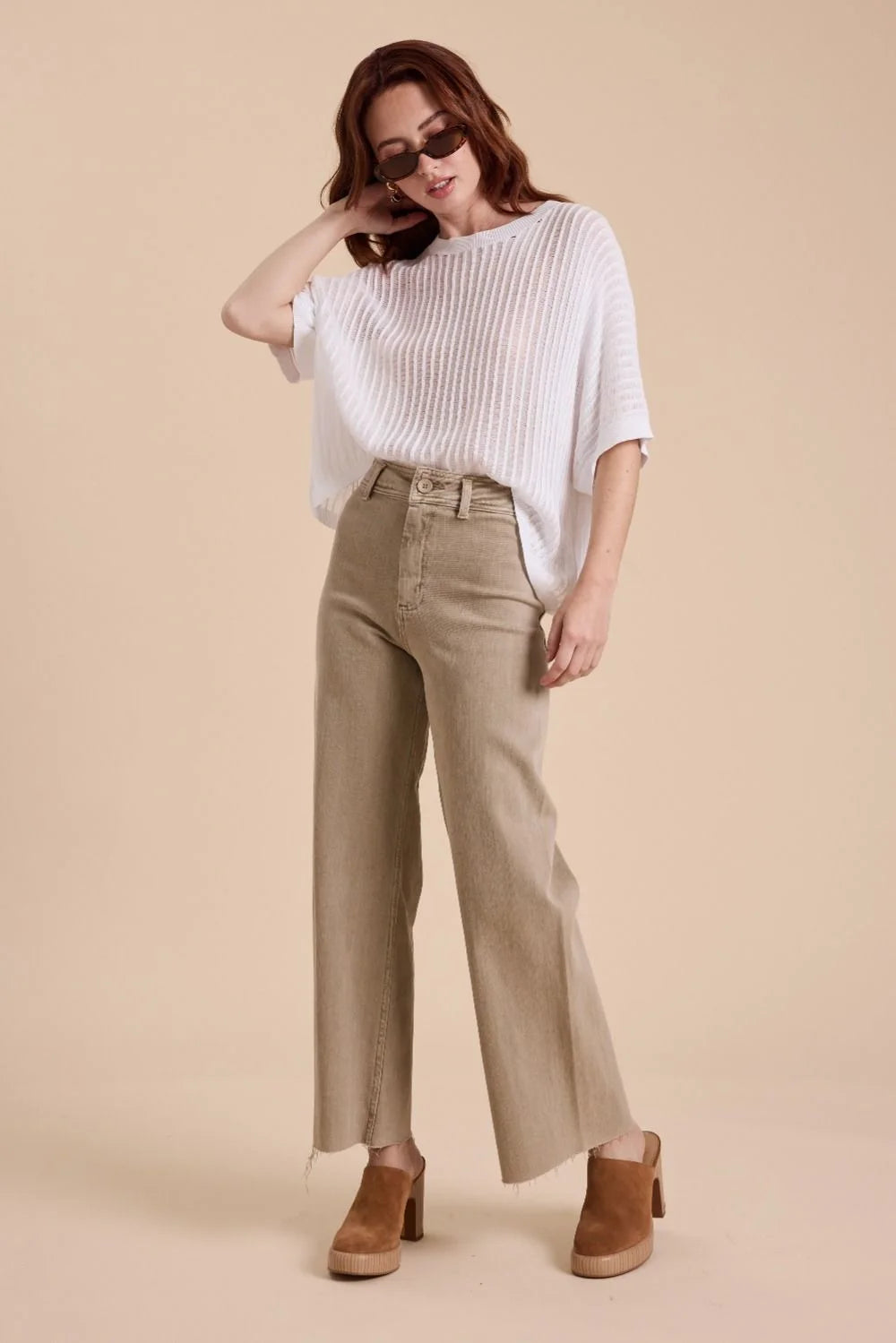 Woman wearing tan straight wide leg denim pants and a white top showcasing style