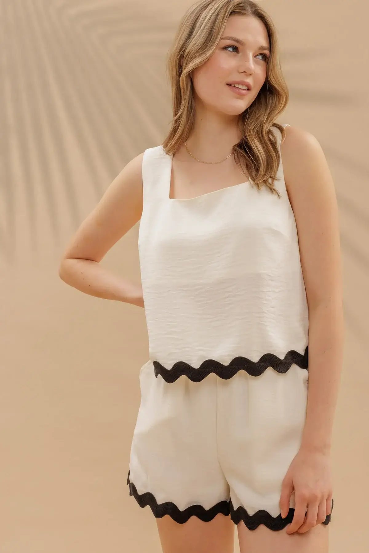 Woman in summer fashion wearing wavy contrast hem sleeveless top with white tank and shorts