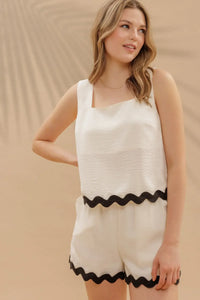 Woman in summer fashion wearing wavy contrast hem sleeveless top with white tank and shorts