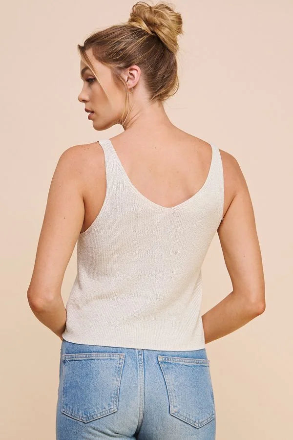 Woman in a white tank top and blue jeans showcasing a lightweight sweater knit design