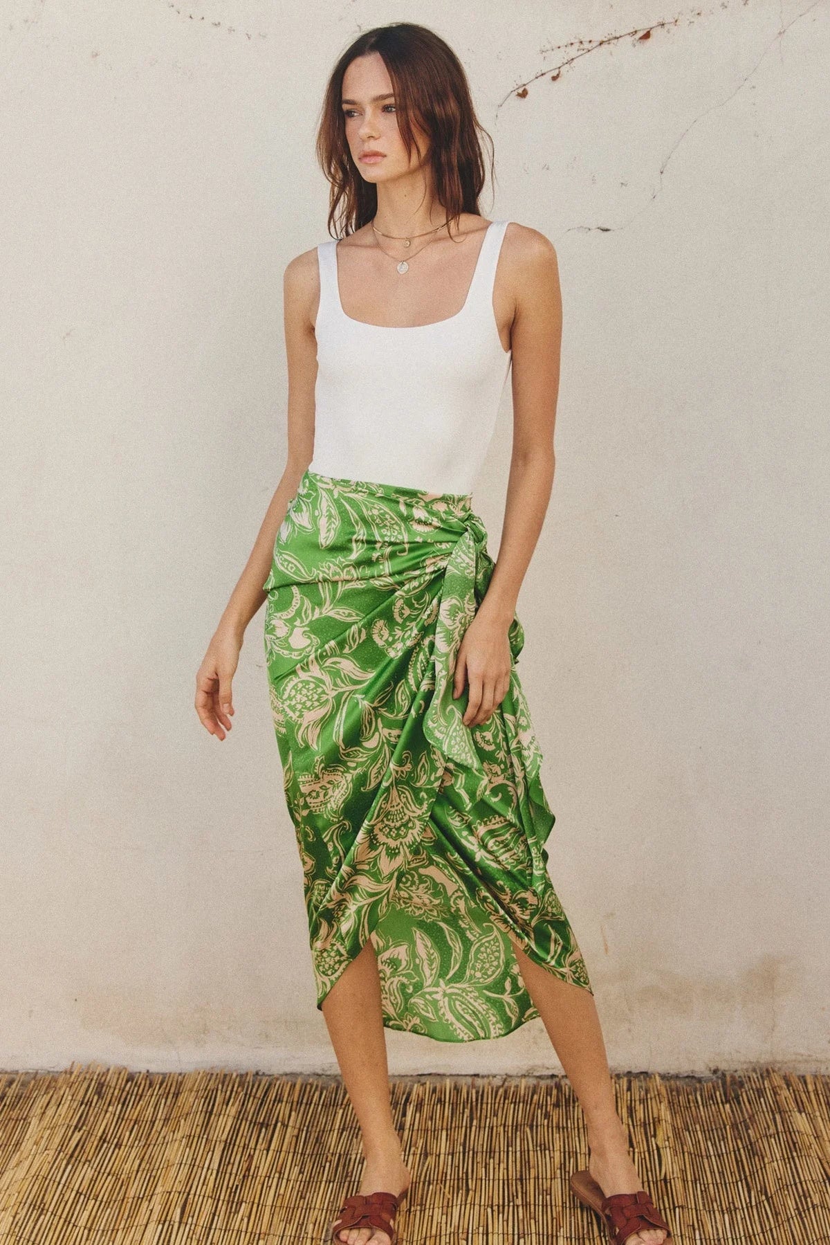 Woman in a white tank top and green tropical wrap skirt embodying a boho, free spirit style