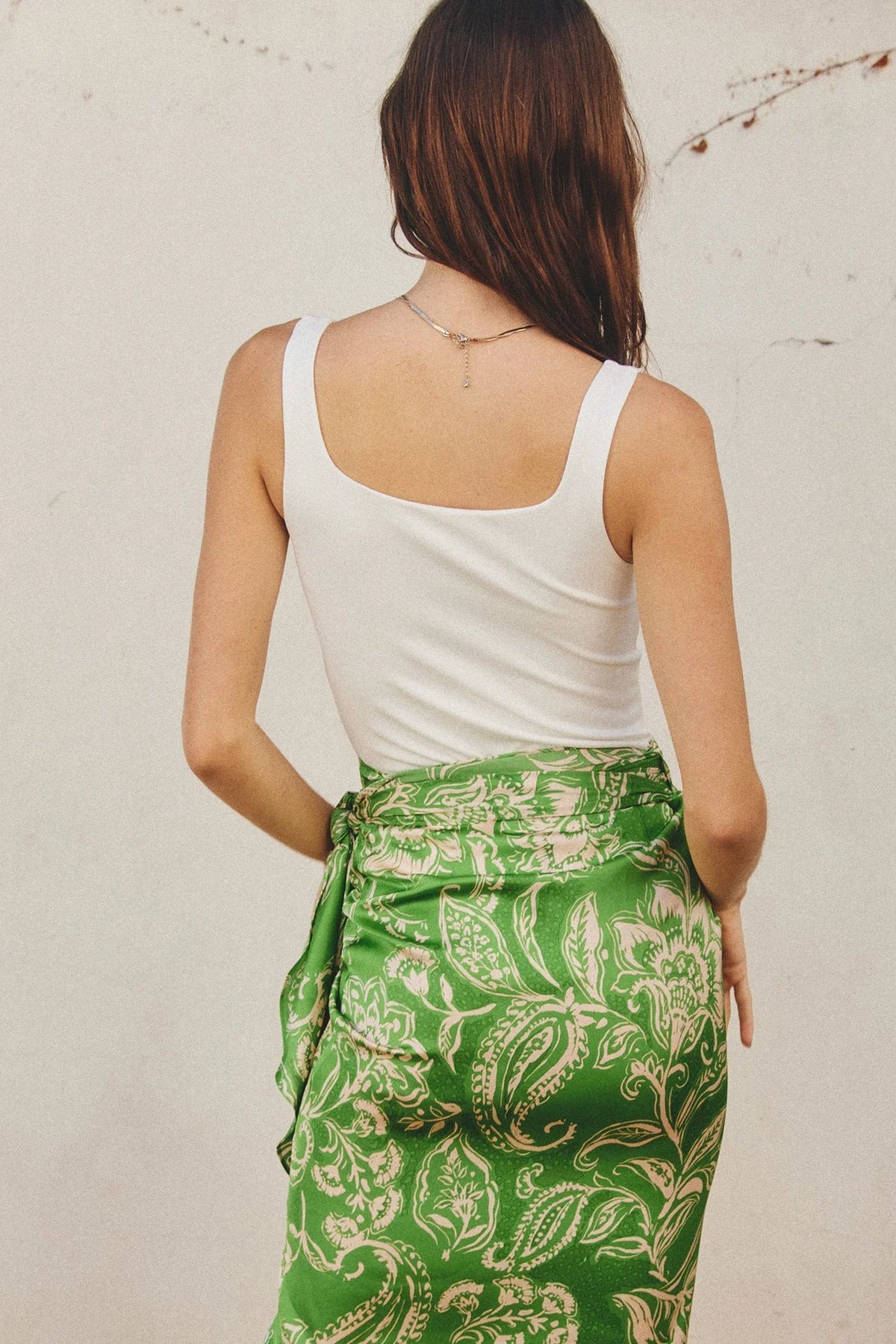 Woman in flowy green patterned skirt and white tank top, embodying free spirit style