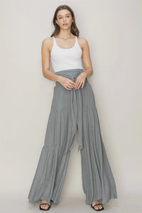 Woman in white tank top showcasing Ruched Tiered Pants with tie-front design