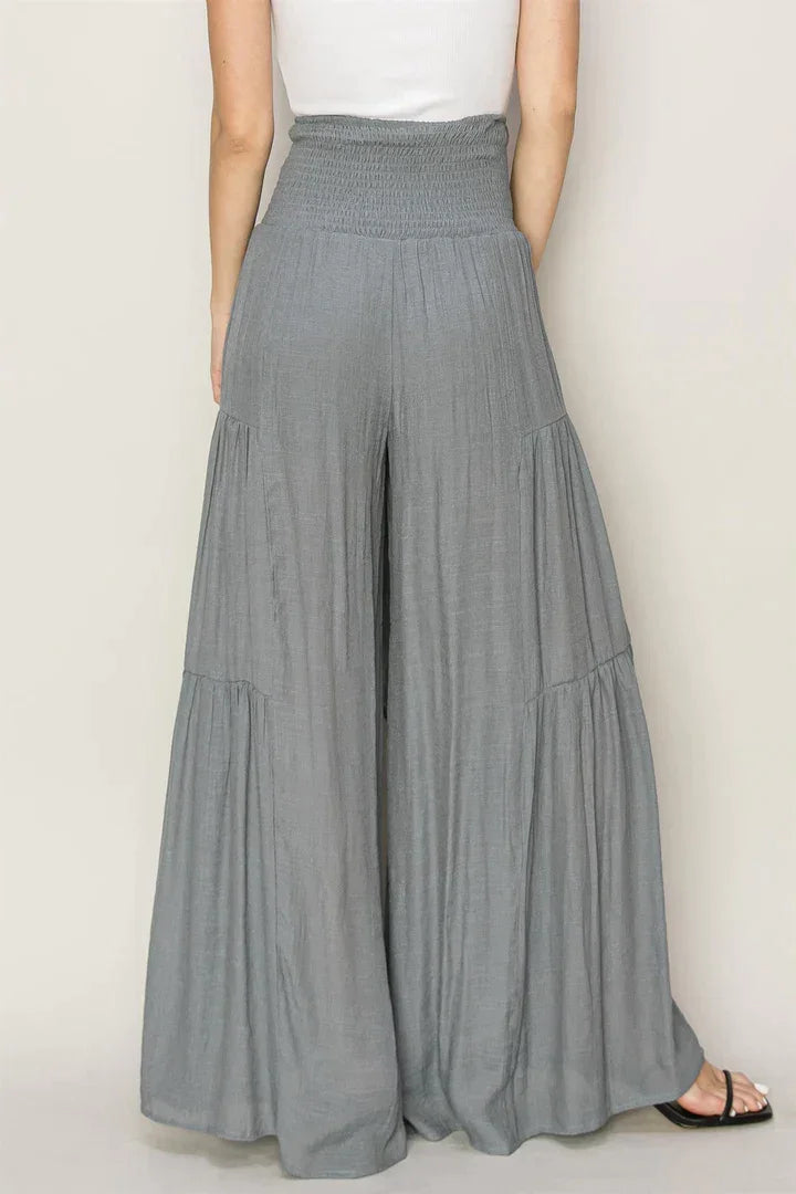 Woman in white tank top and grey ruched tiered pants showcasing modern elegance