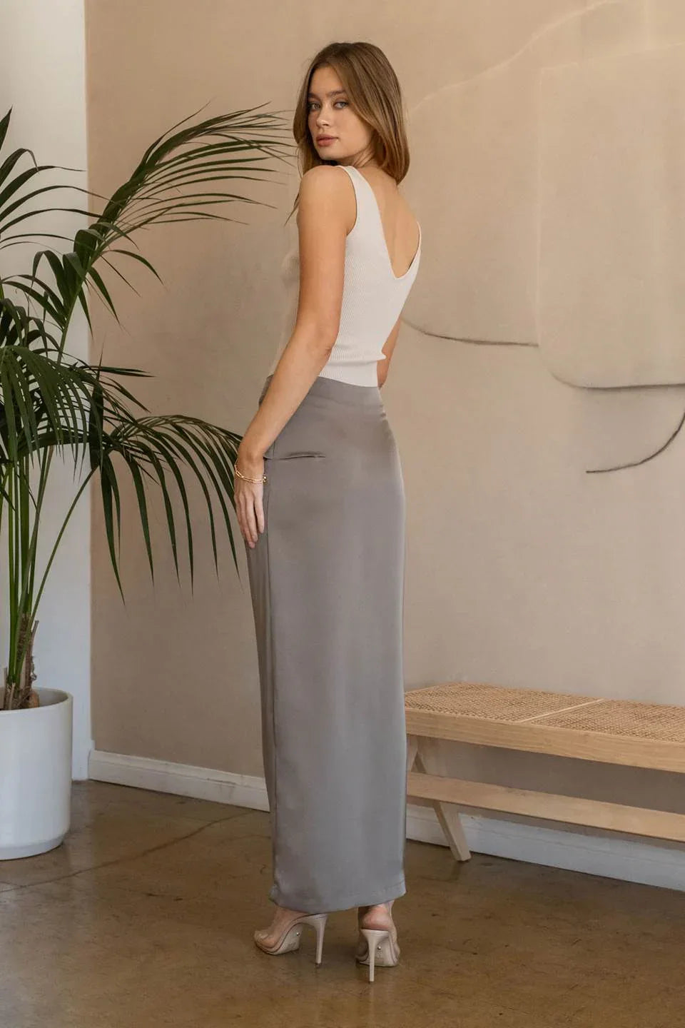 Woman in a white ribbed tank and gray skirt, showcasing boho style