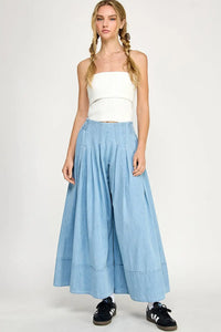 Woman in a white tube top and light blue culottes wearing wide leg denim fabric pants