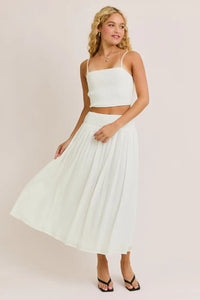 Woman in white smocked spaghetti strap crop top from Daisy Lane Offers