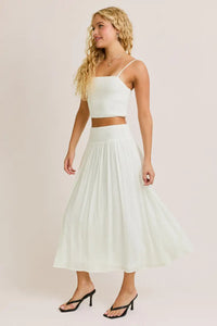 Woman wearing a white smocked spaghetti strap crop top from Daisy Lane Offers