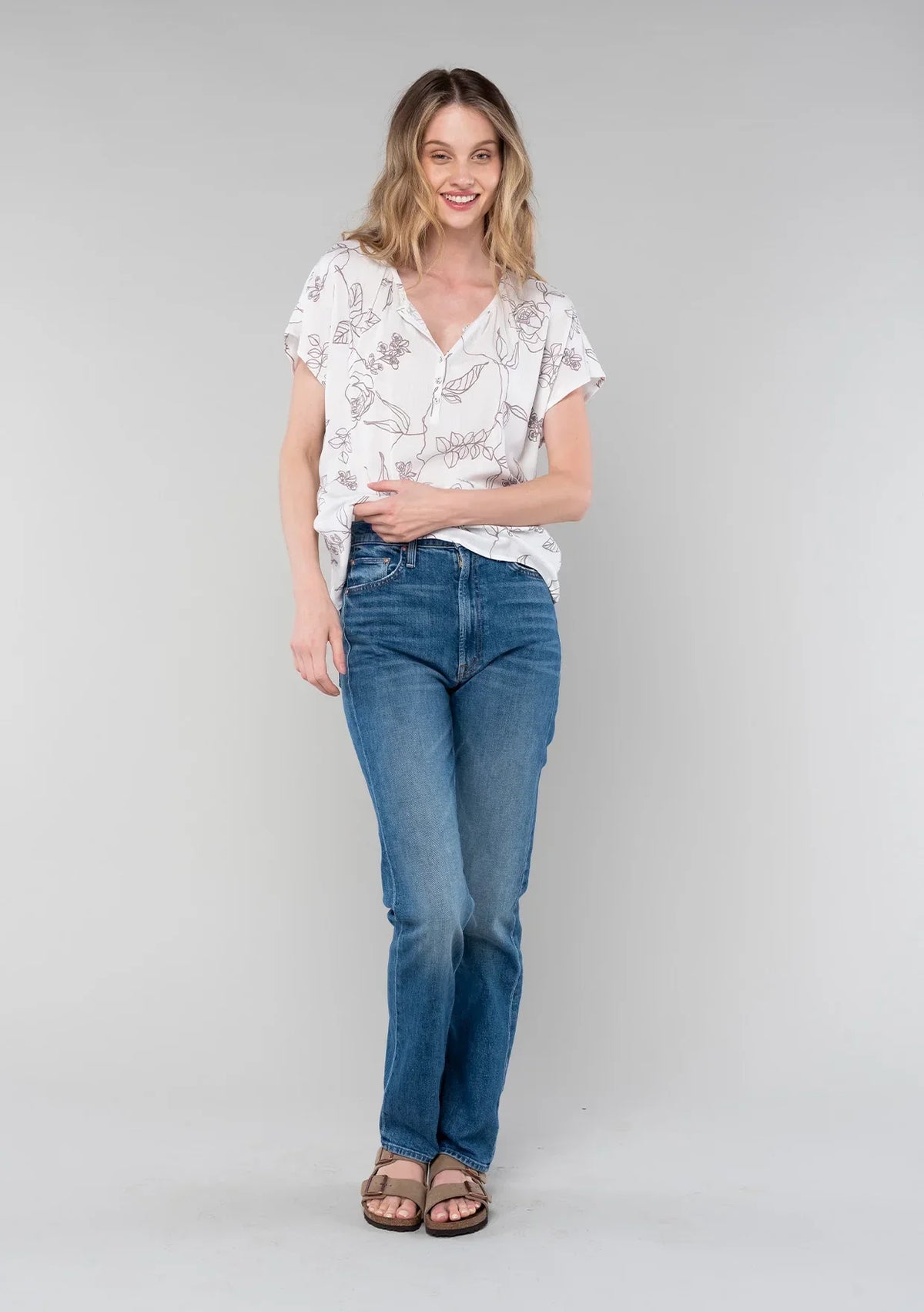 Woman modeling floral short dolman sleeve button top with distressed jeans and brown sandals