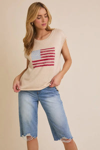 Woman wearing beige shoulder USA flag sweater with wide shoulders and denim capris