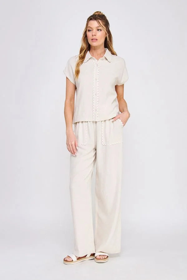 Woman wearing beige linen button pantsuit with collared bow linen shirt