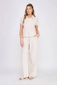 Woman wearing beige linen button pantsuit with collared bow linen shirt