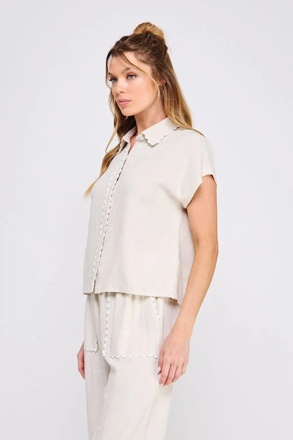 Woman wearing beige collared bow linen pajama set featuring a button-down shirt