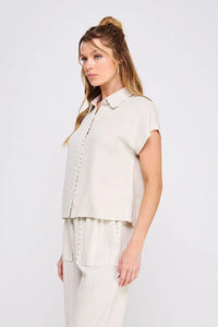 Woman wearing beige collared bow linen pajama set featuring a button-down shirt