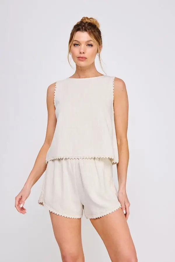 Woman wearing beige sleeveless tulip top with crochet lace trim for elegant summer wear