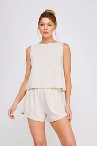 Woman wearing beige sleeveless tulip top with crochet lace trim for elegant summer wear