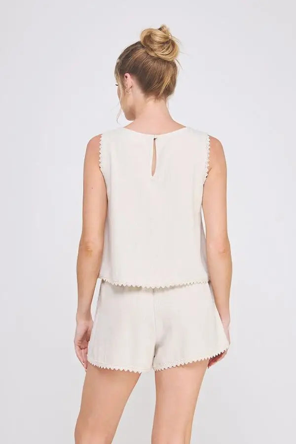 Woman’s beige two-piece shorts set featuring crochet lace trim, elegant sleeveless tulip design for effortless summer wear