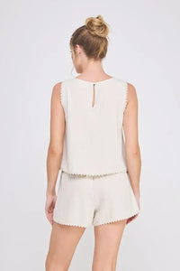 Woman’s beige two-piece shorts set featuring crochet lace trim, elegant sleeveless tulip design for effortless summer wear