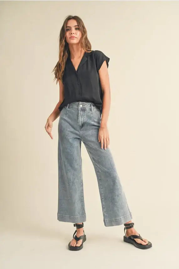 Elegant woman’s black cap sleeve shirt paired with wide-leg jeans for a stylish look