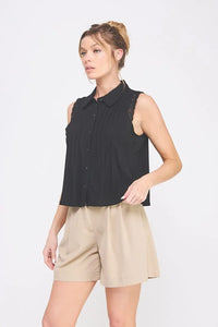 Woman wearing a Pintuck Sleeveless Collard Shirt with Lace Trims and tan shorts at Daisy Lane
