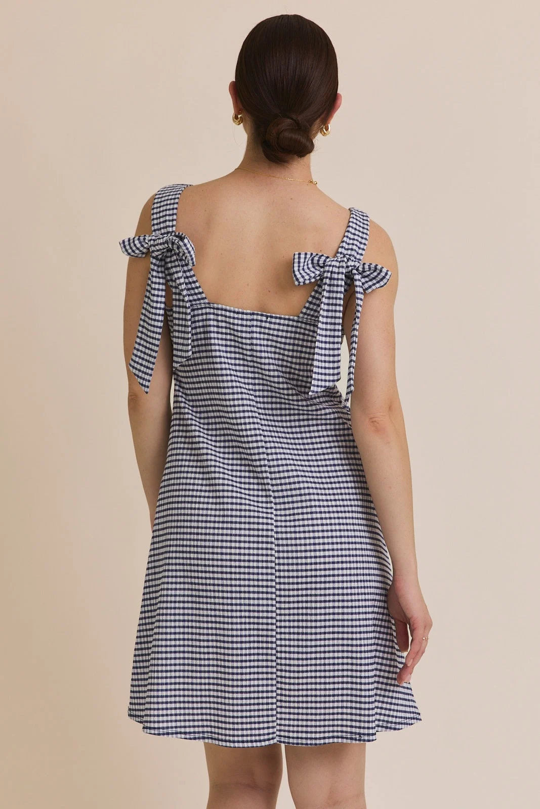 Woman wearing a blue and white stripe sleeveless mini dress with tie shoulders