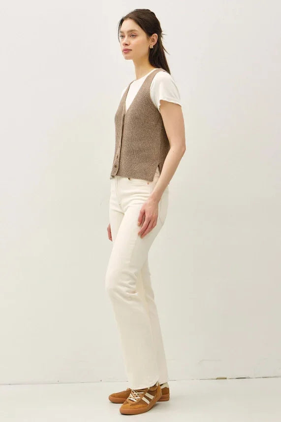 Woman wearing brown chunky V neck sweater vest with white t-shirt and jeans