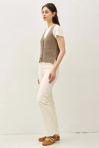 Woman wearing brown chunky V neck sweater vest with white t-shirt and jeans