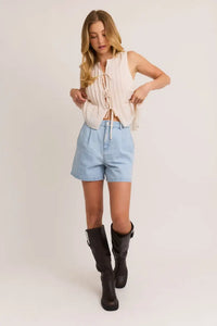 Woman’s casual outfit featuring pleated high waisted denim shorts for stylish comfort