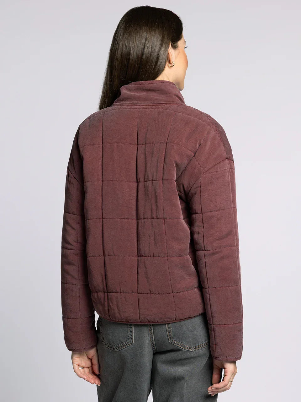 Woman wearing dark plum quilted supply brina jacket with high collar over dark grey pants