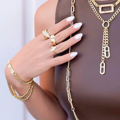 Woman’s hand and torso with gold jewelry showcasing the CZ Script Heart Ring and heart ring