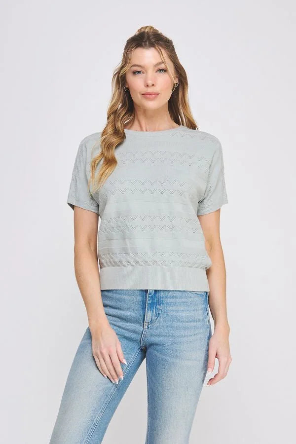 Woman wearing a light blue short sleeve patterned fine gauge knit Dolman top