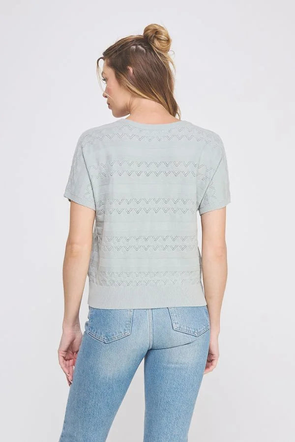 Woman wearing a light green short sleeve patterned fine gauge knit Dolman top with blue jeans