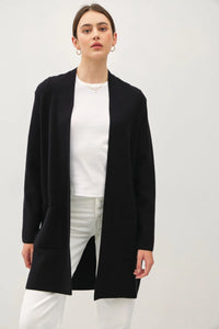 Woman wearing open front classic knit coat over white top and pants