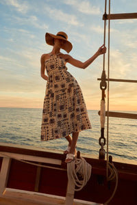 Woman wearing a halter neck abstract print dress with a sun hat, perfect for summer