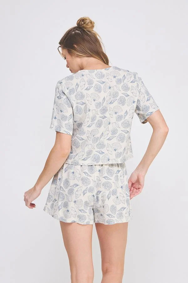 Woman wearing seashell printed linen V neck button-up top and matching two-piece shorts set
