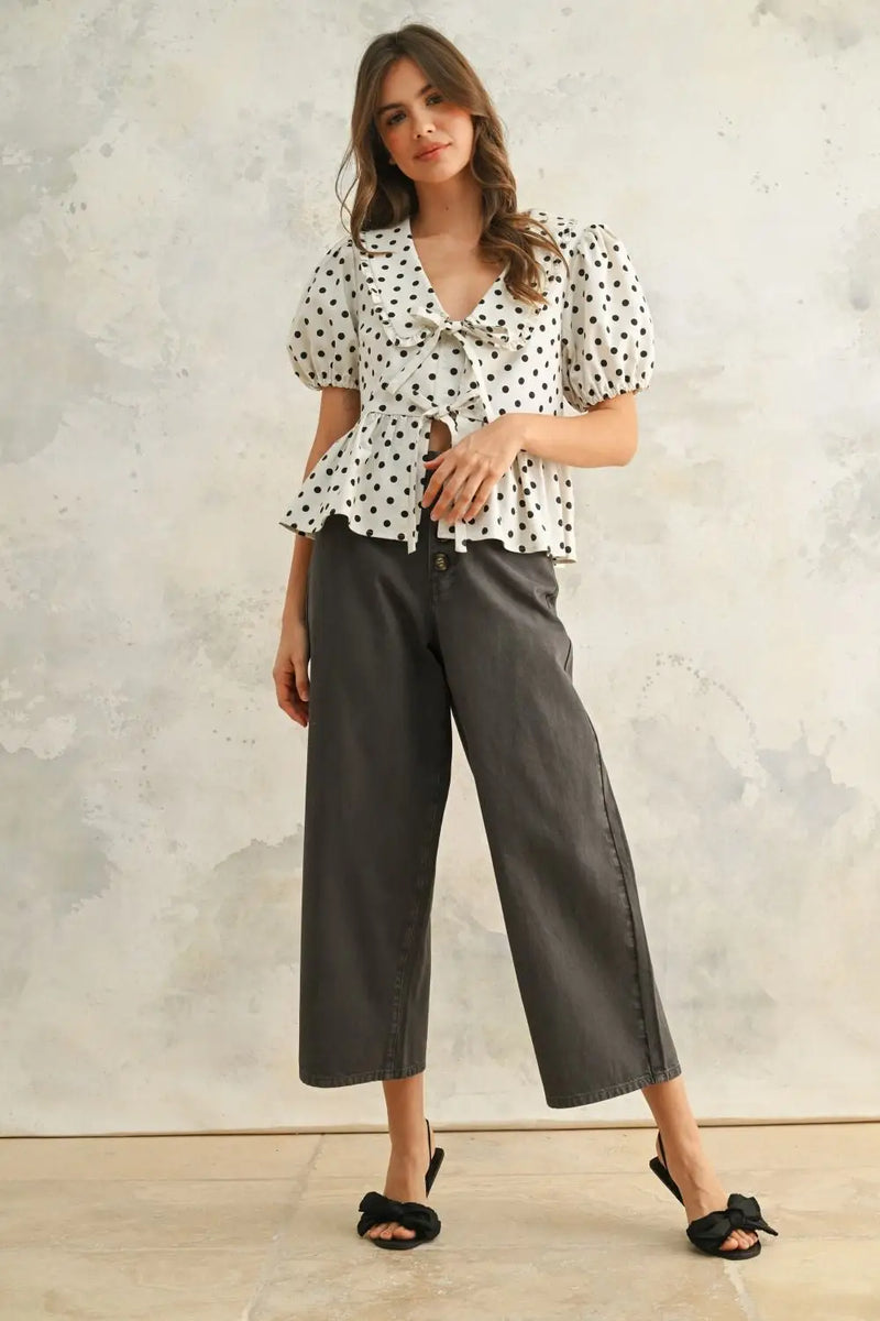 Woman wearing high waisted baggy wide leg pants with polka dot blouse and gray culottes