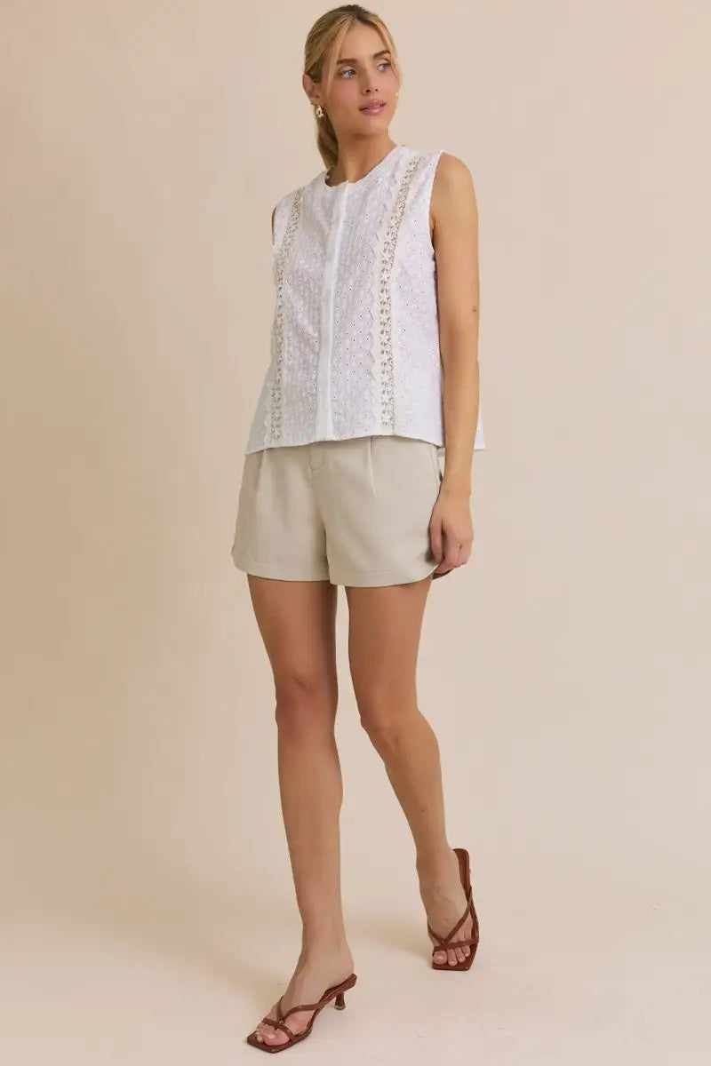Women’s boho chic clothing featuring a sleeveless white eyelet top and beige shorts