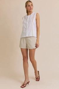 Women’s boho chic clothing featuring a sleeveless white eyelet top and beige shorts