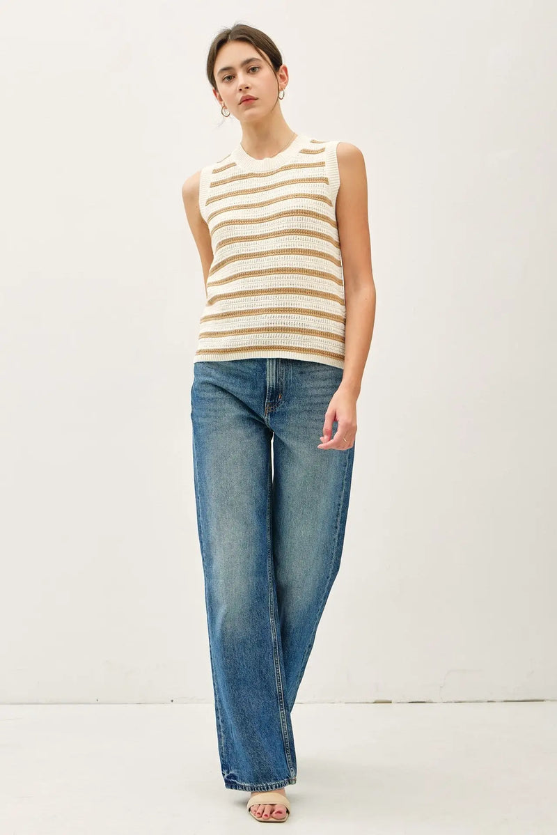 Woman wearing a chunky knit striped sweater tank and blue jeans for a stylish look