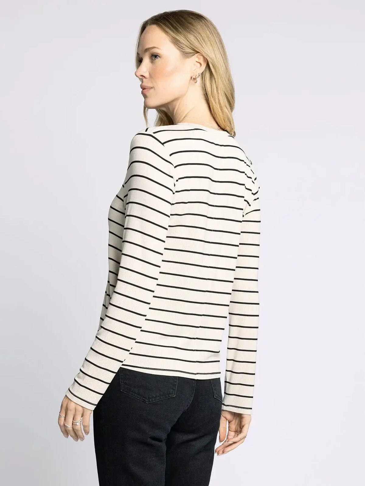Woman wearing striped long-sleeved shirt from THREAD AND SUPPLY LAUREN TOP, perfect for women’s boho chic clothing