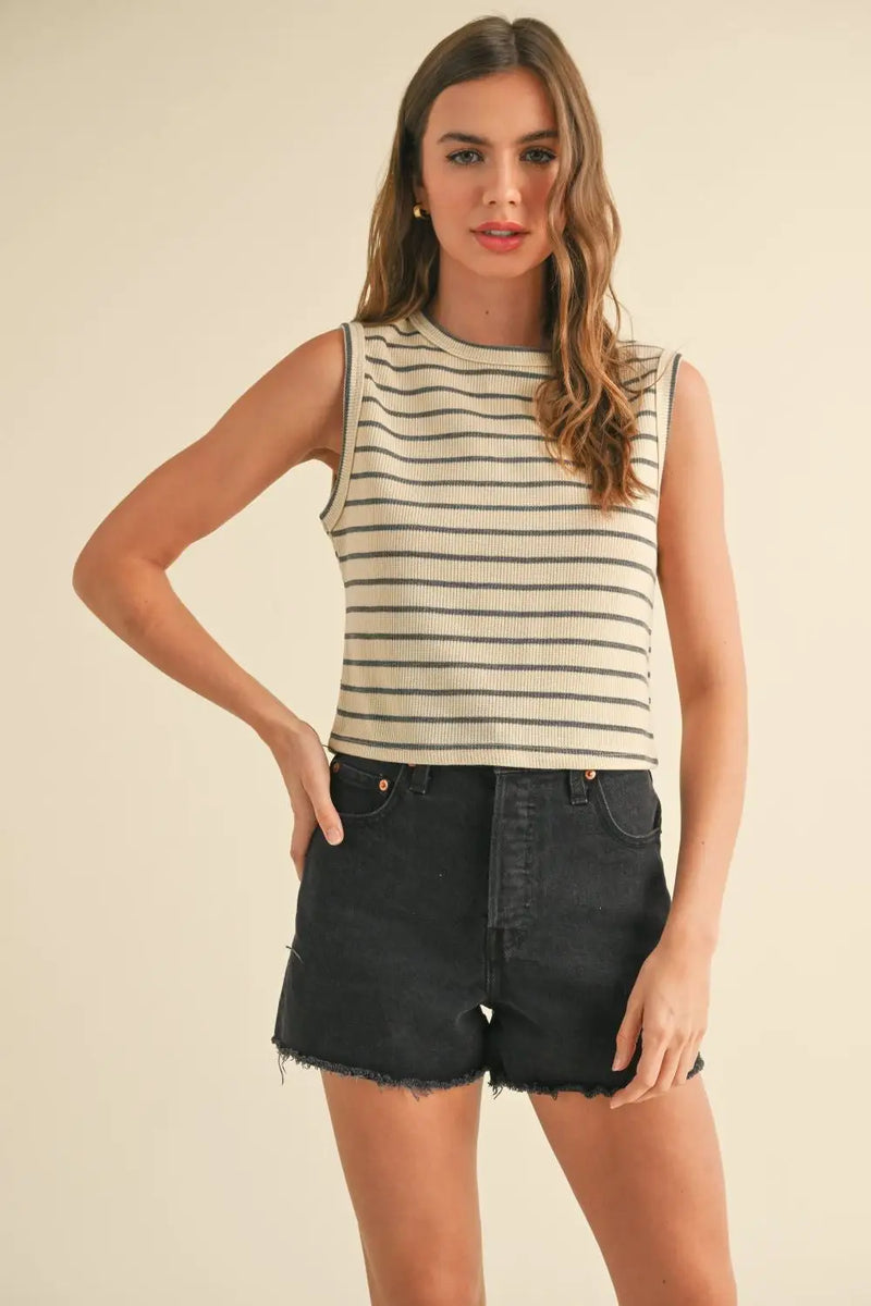 Woman’s striped knitted sleeveless top paired with black denim shorts for a stylish look