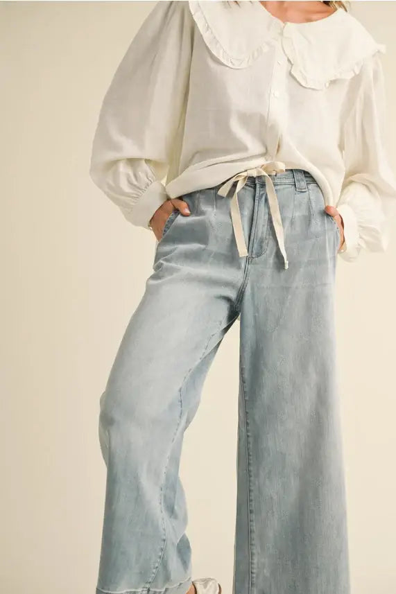 Woman wearing white blouse with light blue WSHD denim pants, ideal for casual style