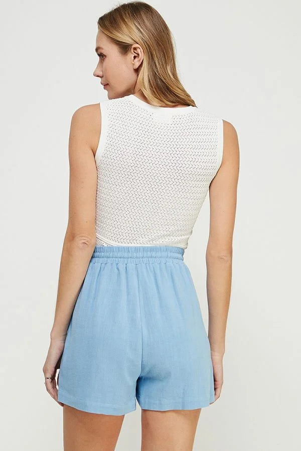 Woman wearing a white fine gauge tank top with mixed pointelle details and blue shorts